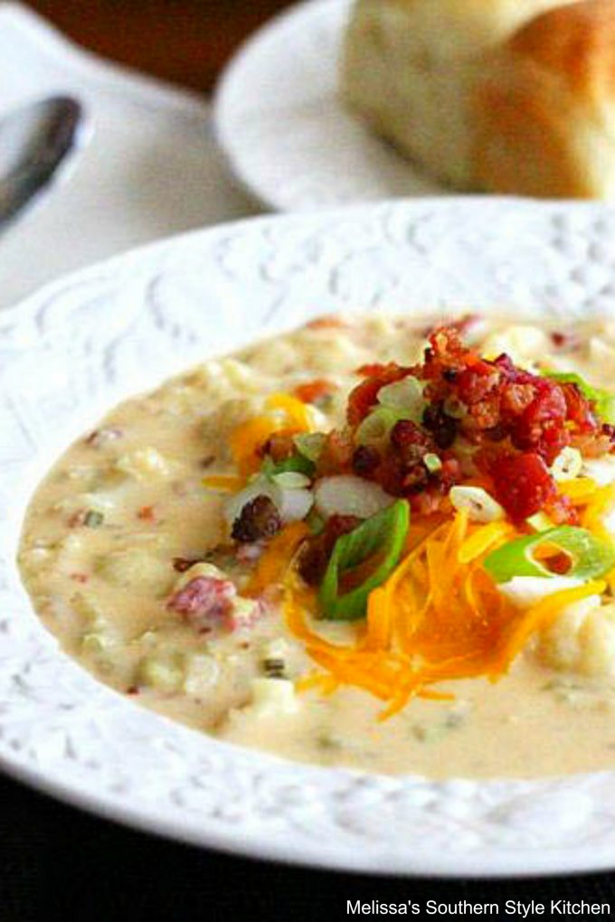 Cheddar Cauliflower Soup with Bacon in a bowl with dinner rolls