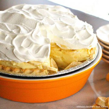 banana cream pie in an orange pie dish with whipped cream on top