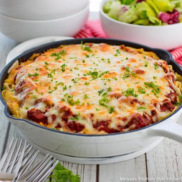 Spaghetti Pie baked in a skillet with a green salad