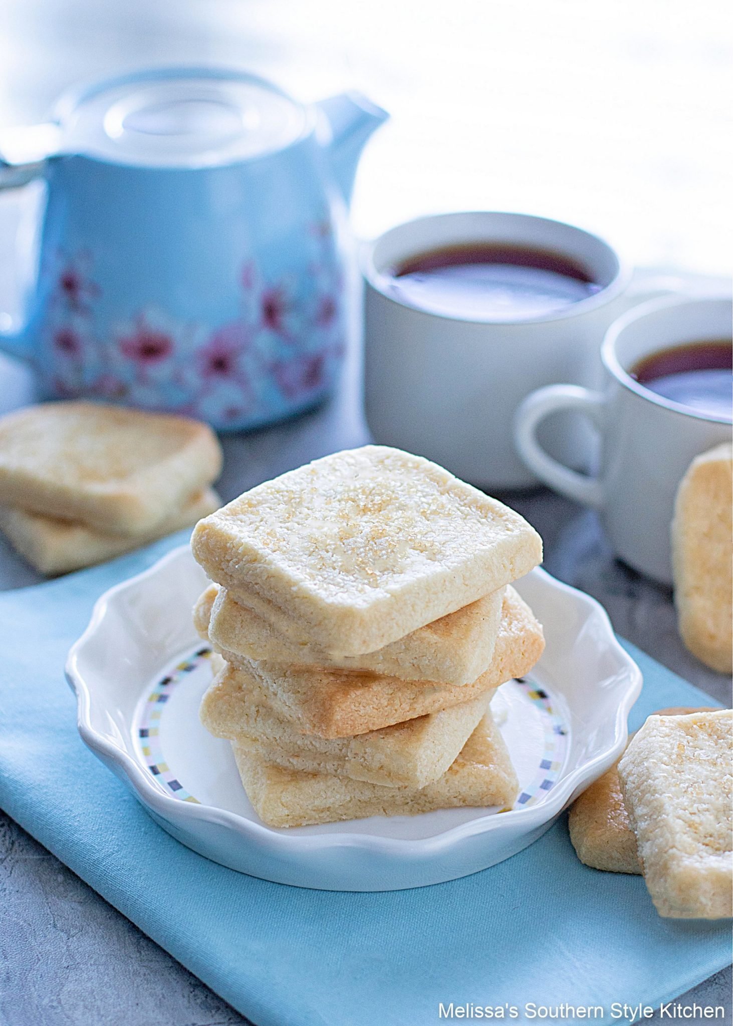 baked shortbread cookies on a white dish with two coffee cups